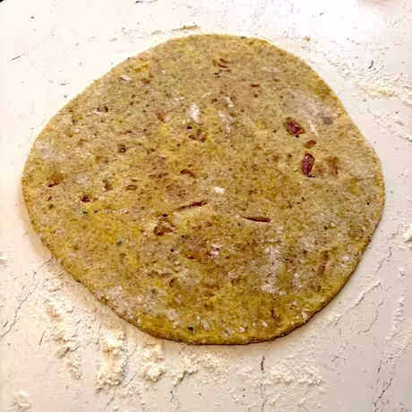 Rolled keema paratha on floured surface.