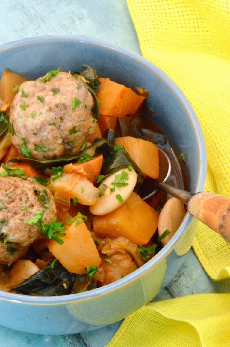 Partial view of swede and bean stew in a bowl with dumplings and spoon.