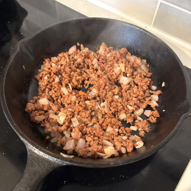 Vegan mince frying in cast iron skillet.