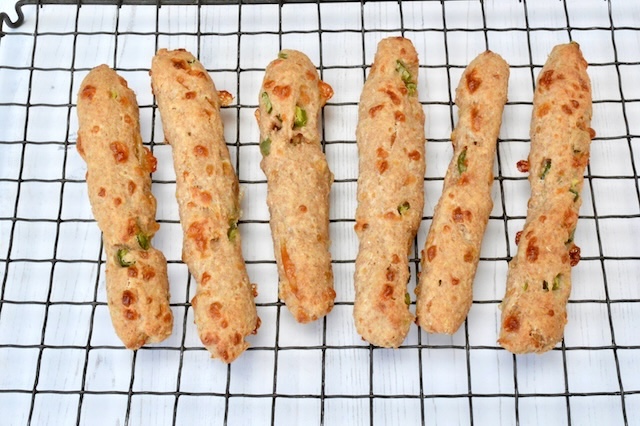 Cheese and chilli wholemeal spelt breadsticks cooling on wire rack.