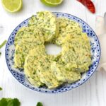 Slices of chilli, lime and coriander butter laid as a circle on a plate.