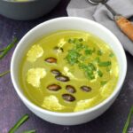 Whole bowl of three-cornered leek and potato soup topped with roasted pumpkin seeds.