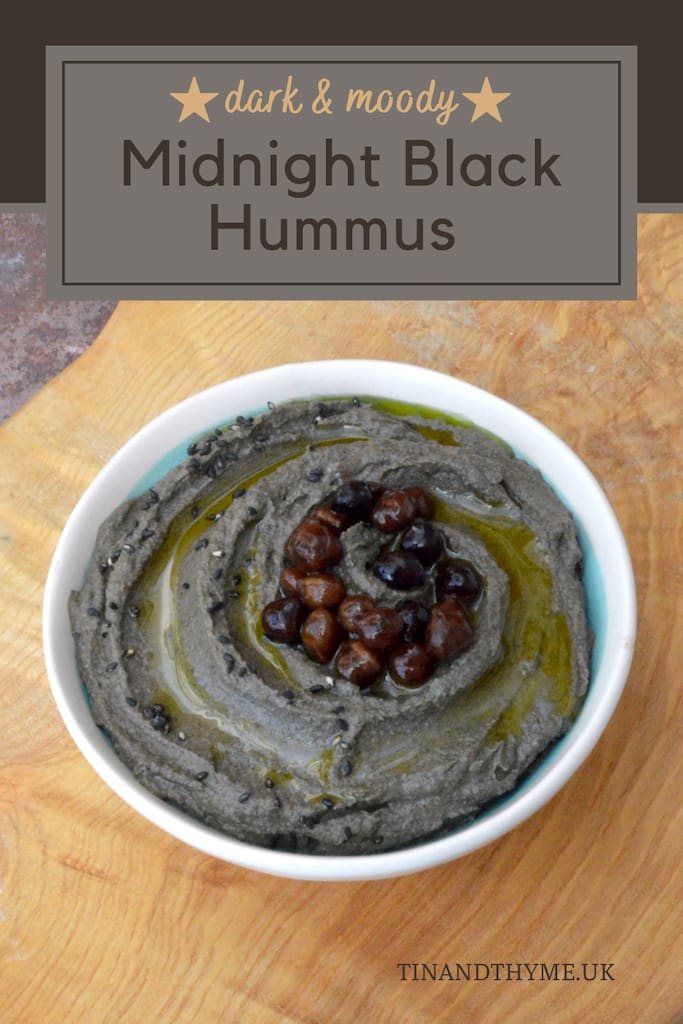 A bowl of midnight black hummus with a topping of chickpeas, black sesame seeds and olive oil.
