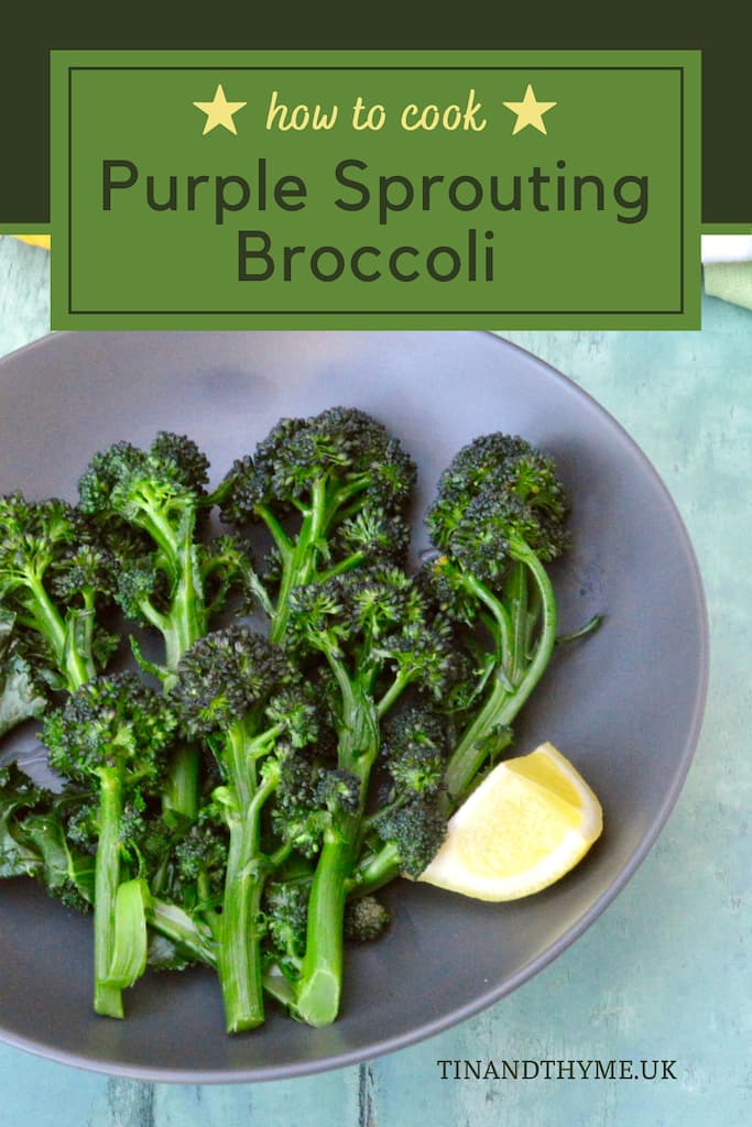 Cooked purple sprouting broccoli in bowl with lemon wedge.