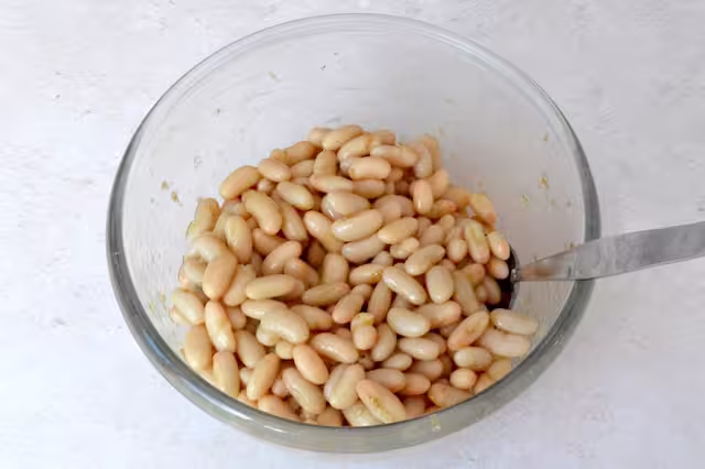 Bowl of cannellini beans marinating in dressing.