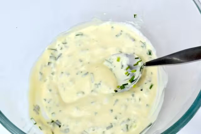 Chives stirred into dressing in bowl.