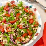 Bowl of Italian cannellini bean salad with servers on the side.