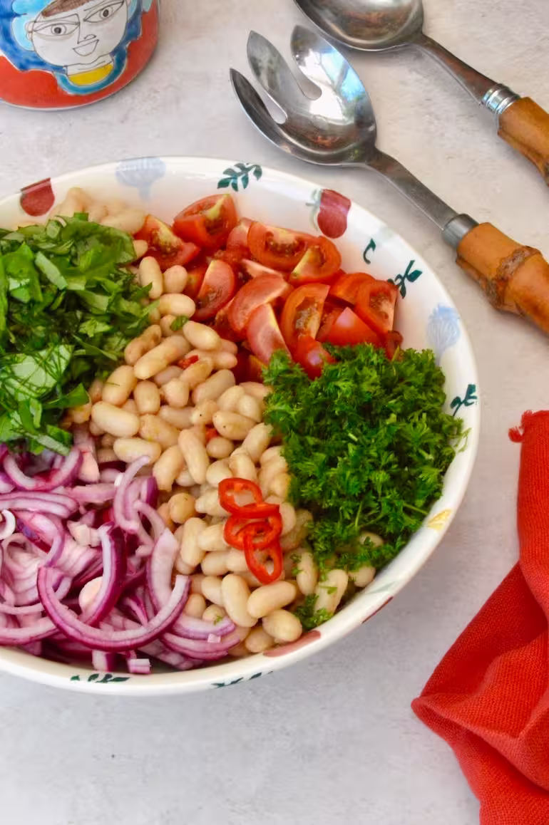Bowl of Italian bean salad ingredients awaiting mixing.