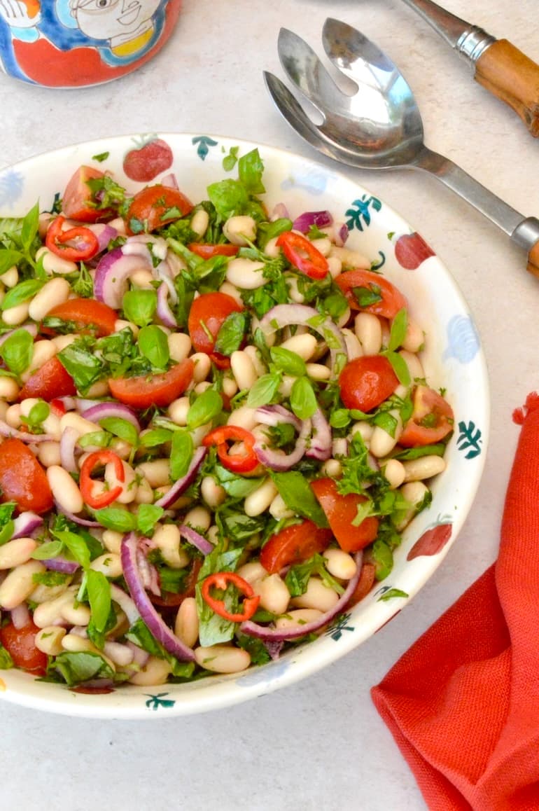 Bowl of Italian cannellini bean salad with servers on the side.