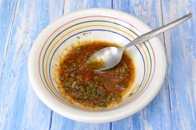 Marinade ingredients mixed together in bowl with spoon.