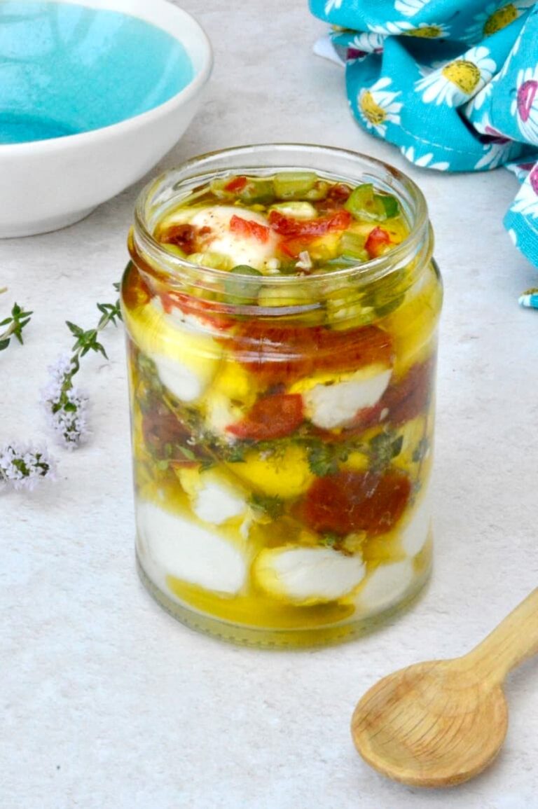 Jar of mozzarella balls marinading in olive oil and other ingredients.