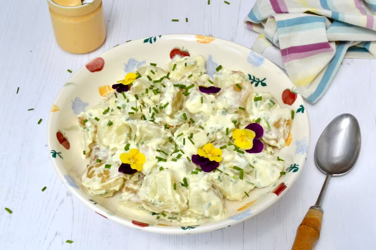 Bowl of homemade simple potato salad with edible flowers on top.