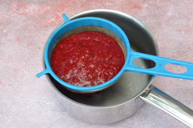 Blitzed raspberries in sieve.