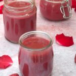 Three open jars of homemade raspberry rose curd.