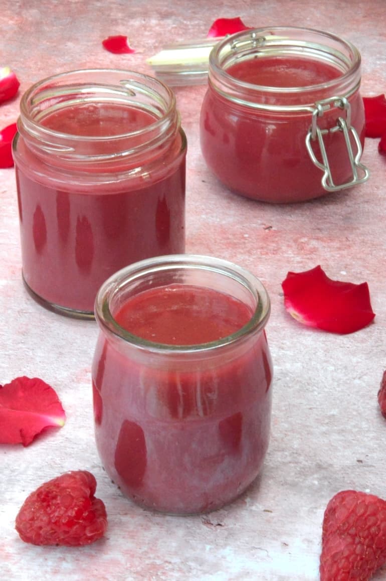 Three open jars of homemade raspberry rose curd.