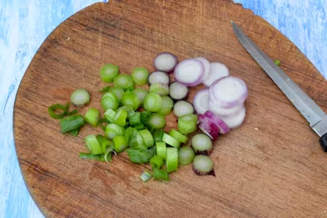 Red salad onion sliced on board with knife.