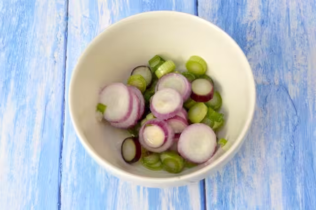 Bowl of red salad onion slices pickling in lemon juice.