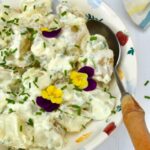 Simple potato salad with creamy dressing and chives. Decorated with edible flowers.