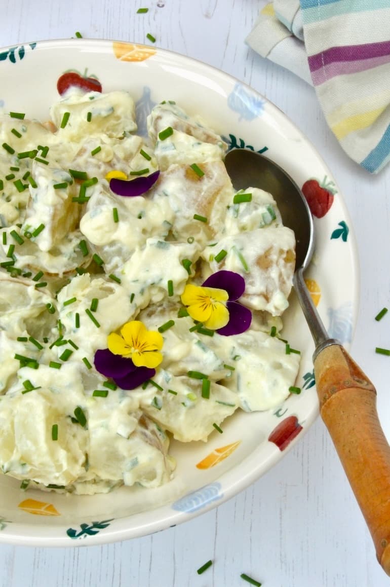Simple potato salad with creamy dressing and chives. Decorated with edible flowers.