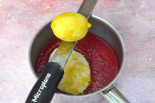 Zesting lemon with microplane into pan.