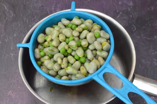 Cooked beans and peas draining in sieve.