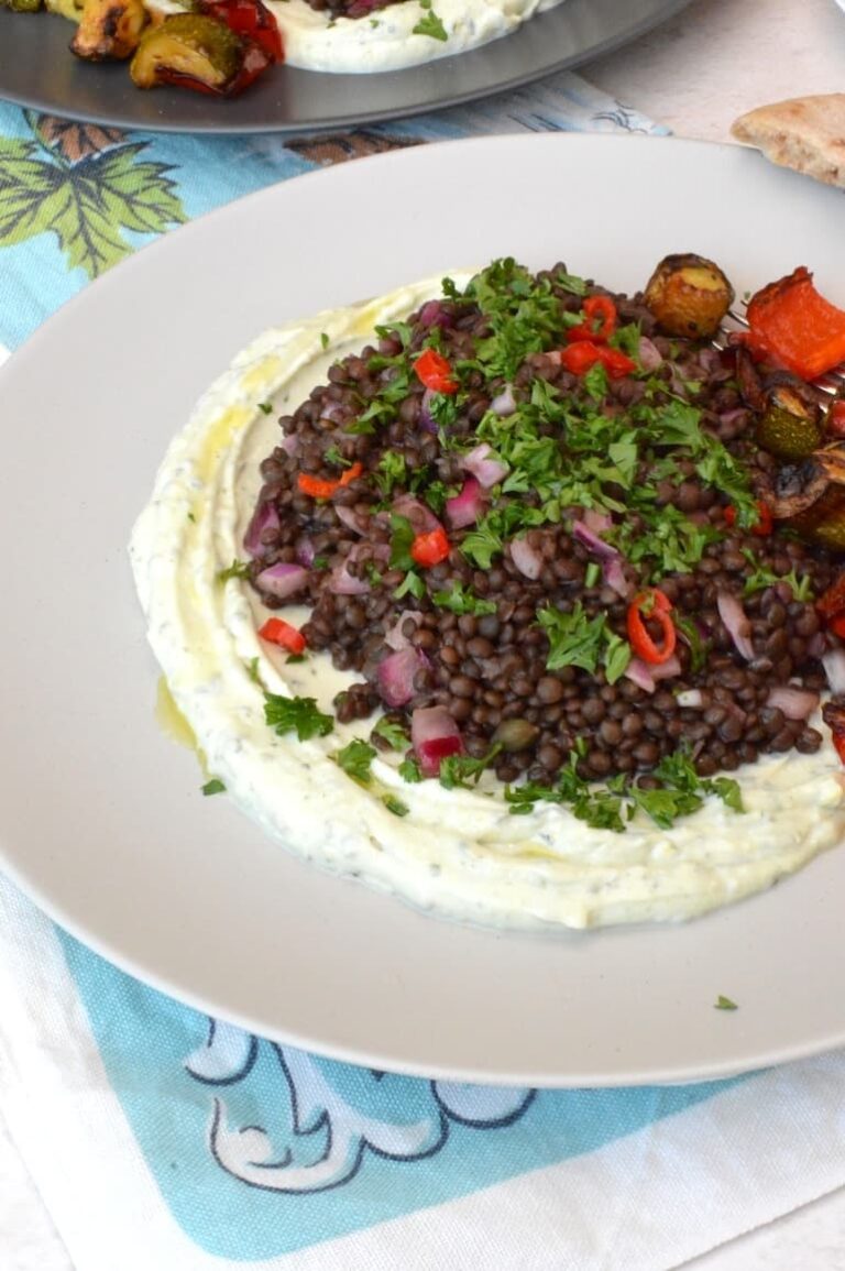 Plate of black lentil salad on bed of whipped ricotta cheese.
