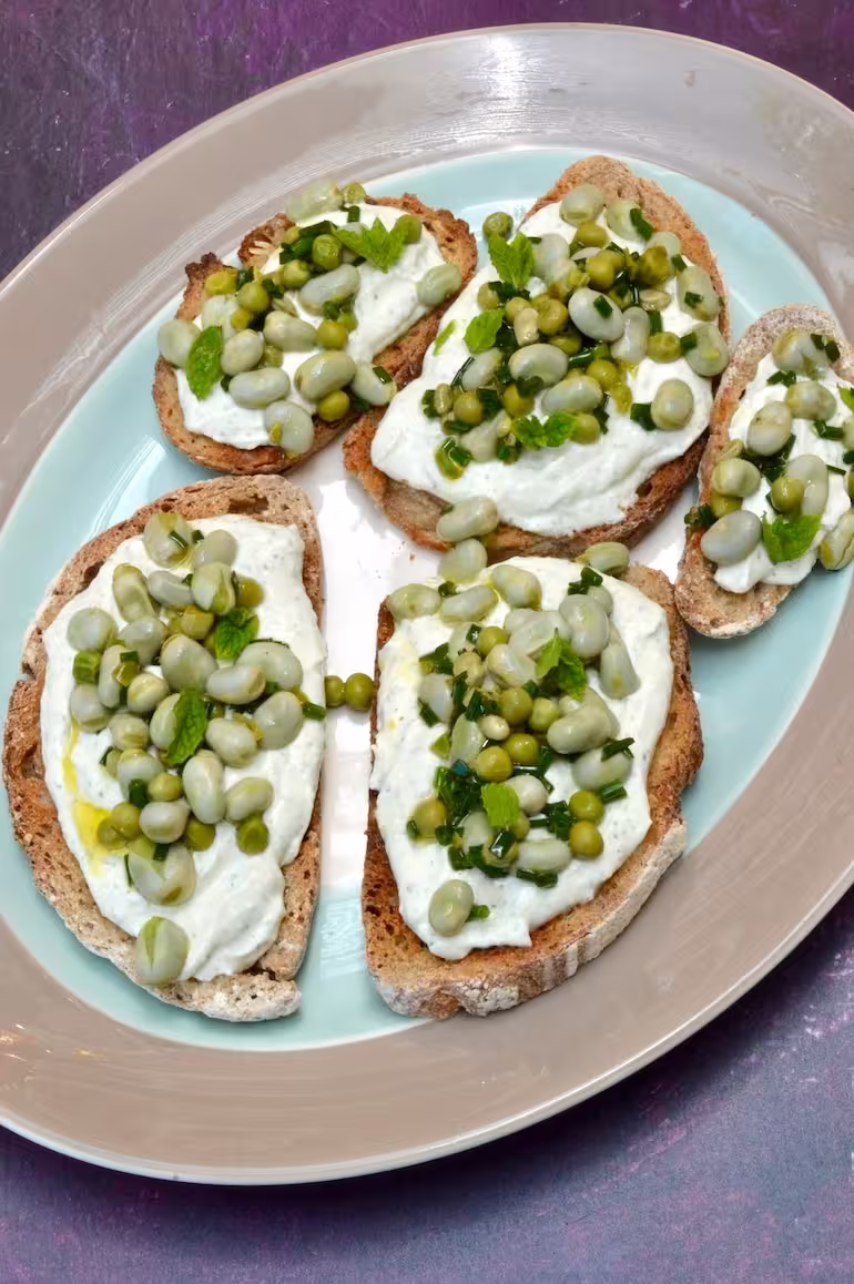 Platter of broad bean toast slices with whipped cottage cheese.