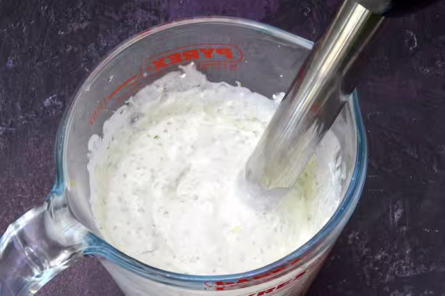 Cottage cheese blended with mint leaves in jug.