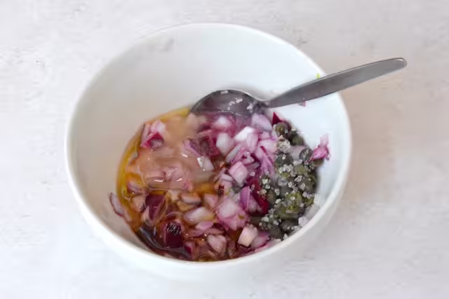 Pickled onion dressing ingredients in bowl with spoon.