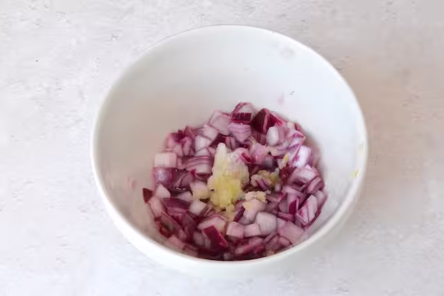 Crushed garlic added to bowl of pickled red onions.