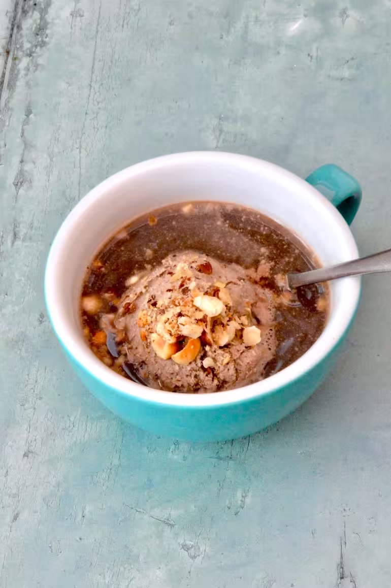 Hojicha affogato in a cup with toasted hazelnuts and spoon.