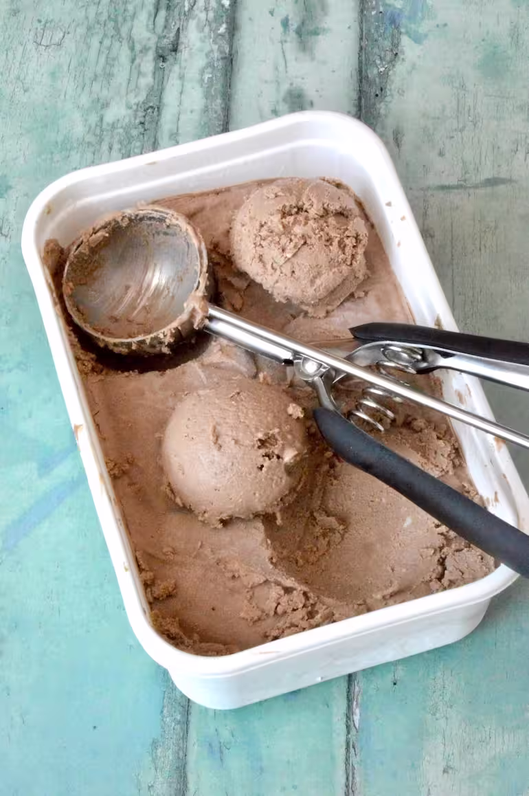 Scoops of homemade hojicha ice cream in tub with scoop.