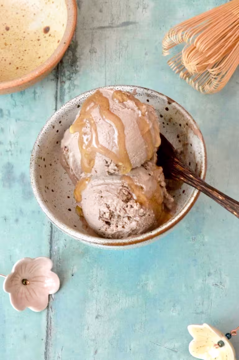 Hojicha ice cream scoops in bowl with drizzle of honey and spoon.