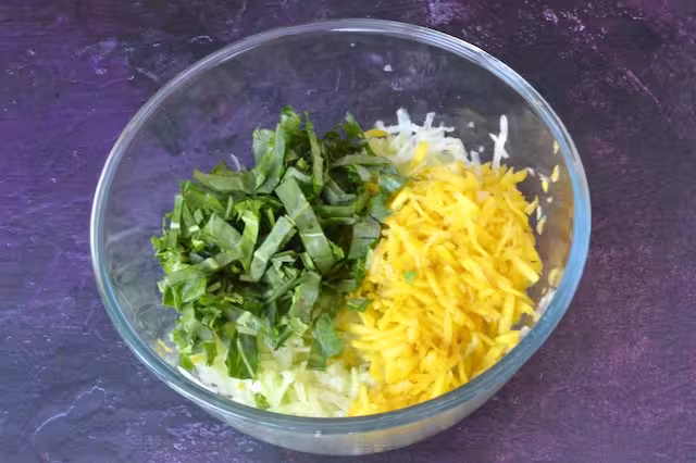 Sliced kohlrabi leaves added to mixing bowl.