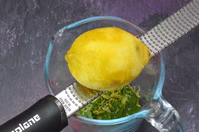 Lemon being zested into jug.