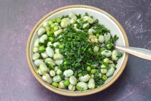Snipped chives added to bowl of beans and peas.