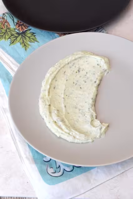 Whipped lemon herb ricotta spread on plate.