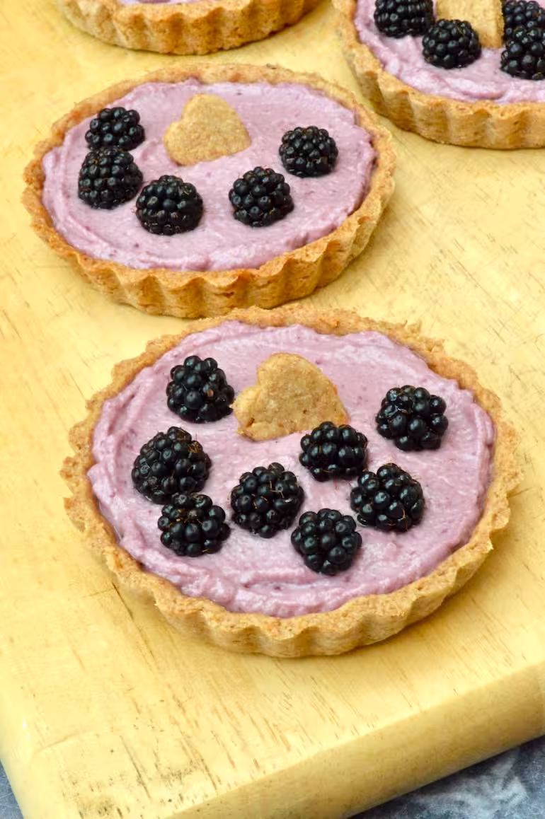 Close up of two homemade blackberry tarts with hazelnut crust.
