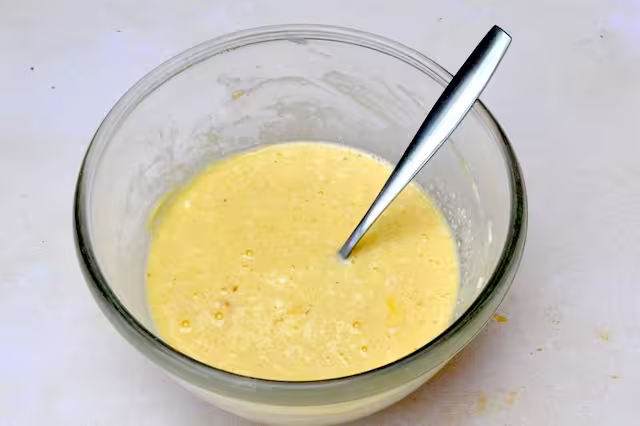 Beaten eggs and ricotta cheese in mixing bowl with fork.