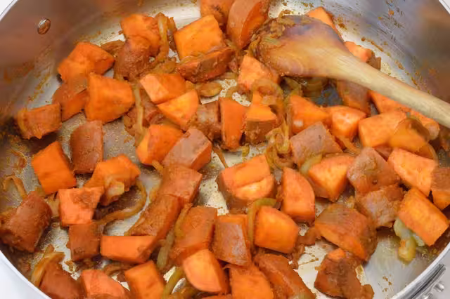 Frying curry paste with veg in pan.