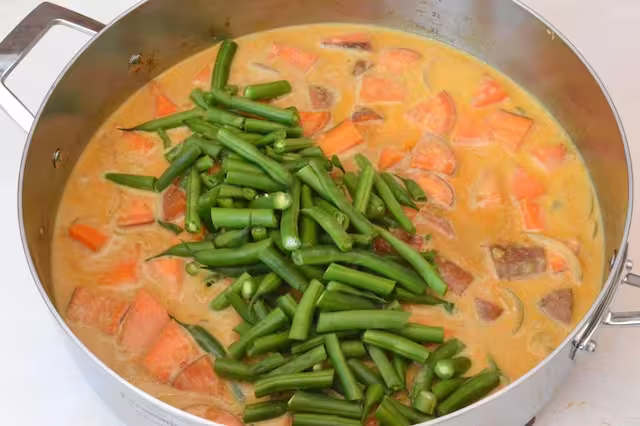 Green beans added to pan of sweet potatoes and coconut milk.