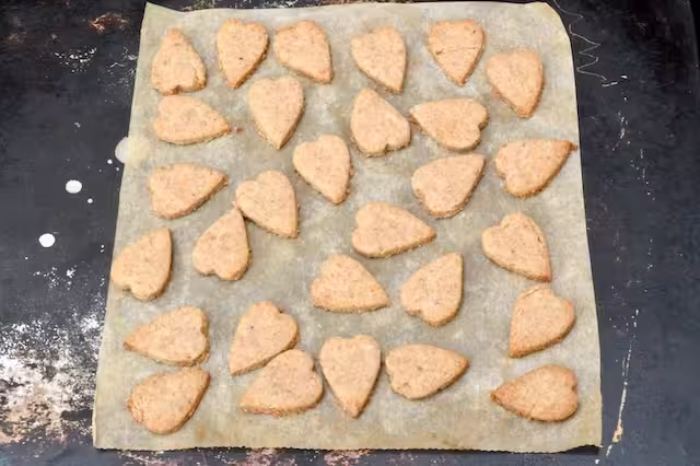 Mini hazelnut heart biscuits on baking tray.