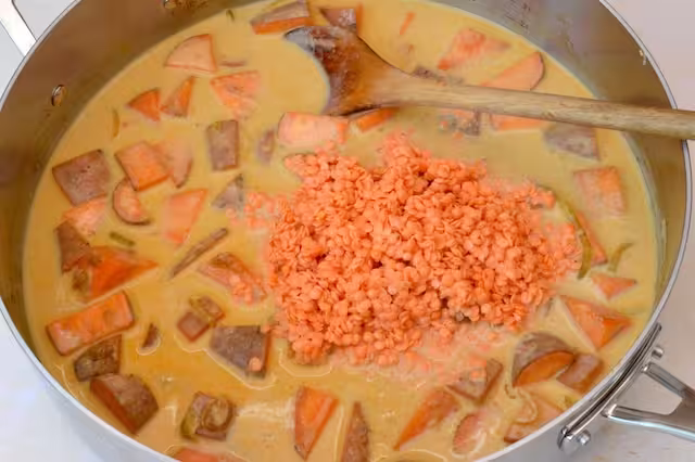 Lentils added to coconut milk in pan.