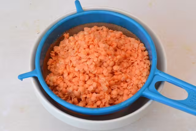 Lentils draining through a sieve.