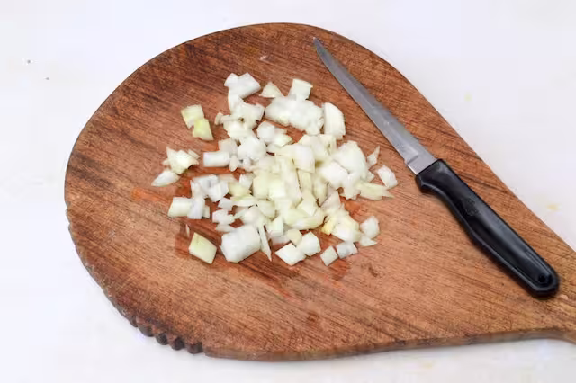 Diced onions on chopping board with knife.