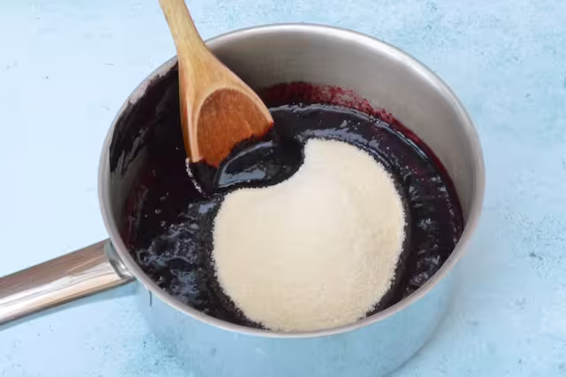 Sugar added to fruit puree in pan.