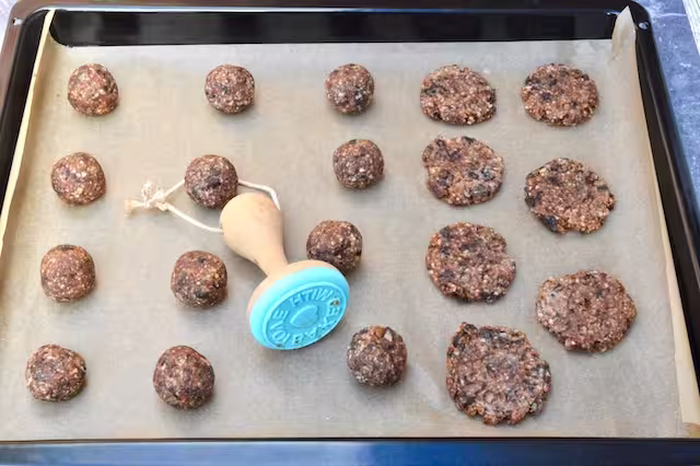Some cookie dough balls on baking sheet stamped.