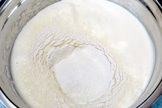 Flour sifted into whisked egg mixture in bowl.