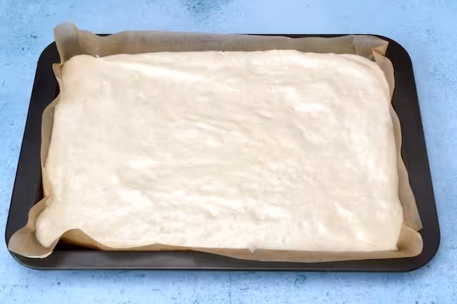 Raw genoise sponge mix in Swiss roll tin.