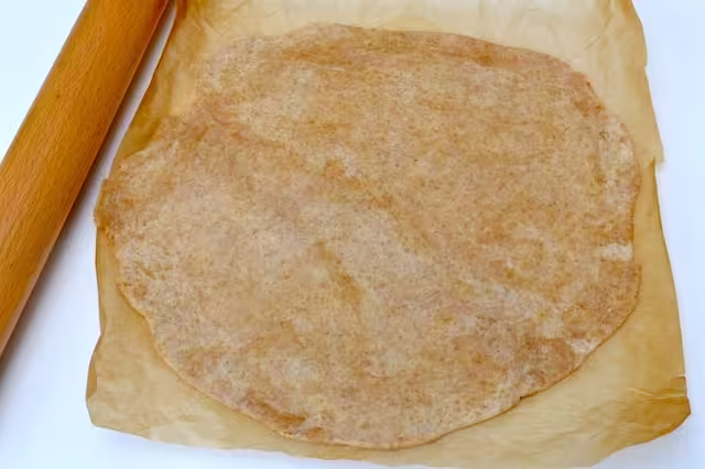 Wholemeal spelt pastry dough rolled out into a rough circle on baking paper.